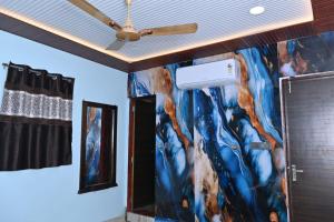 マウント・アブにあるHotel Unique Villaの天井ファン付きの客室で、壁に絵画が飾られています。