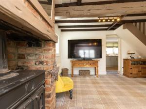 un soggiorno con TV e muro di mattoni di Silver Cottage a Scruton