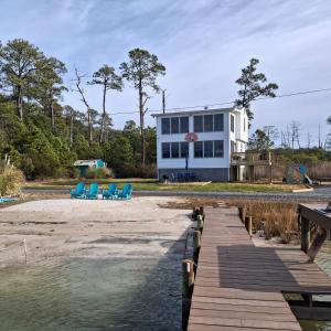 a house on the beach with a dock and chairs at Little Oyster Oasis in White Stone