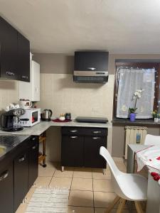 una cocina con armarios negros y una silla blanca en Casa Silvia, en Chambave