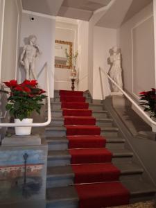 a red carpeted staircase in a building with two statues at Hotel Tourist House in Florence