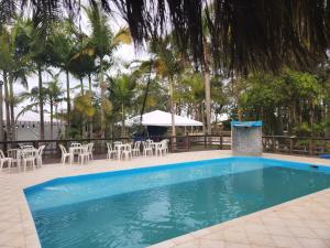 een zwembad met stoelen en een tafel en parasol bij Pousada Villa Da Guarda in Guarda do Embaú