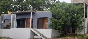 una casa azul con una pared blanca y un árbol en Ponta Family holiday house, en Ponta do Ouro