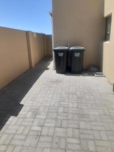 due bidoni della spazzatura sono appoggiati accanto a un edificio di Bird Whistle a Zeekoevlei