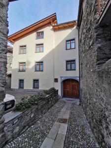 ein Gebäude mit einer Holztür und einer Steinmauer in der Unterkunft Curt di Manai Charme Apartments in Tirano