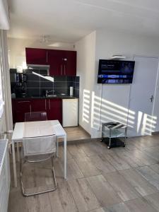 une cuisine avec des placards rouges et une table blanche dans l'établissement STUDIO 50m de gare de st-louis, à Saint-Louis