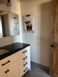 een badkamer met een commode met een koe op de muur bij Willowbend Bunkhouse 