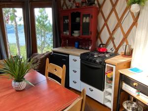 a kitchen with a stove and a dining table at Yourte Forêt des Murmures in Sacré-Coeur-Saguenay +4 photos