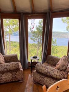 a living room with two chairs and a table and large windows at Yourte Forêt des Murmures in Sacré-Coeur-Saguenay