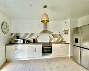 a kitchen with white cabinets and a clock on the wall at Two-bedroom suite in Montévrain