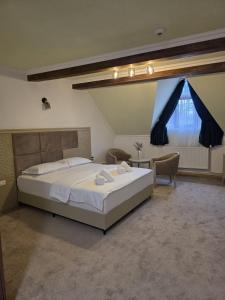 a bedroom with a large white bed and a window at Pensiunea La Cetate in Târgu Neamț