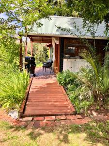 a wooden walkway leading to a house with a grill at RIMU CABIN At the Bridge in Motungarara