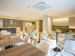 een eetkamer met tafels en witte stoelen bij Solar Explore Botanico in Curitiba