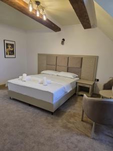 a bedroom with a large bed and a chair at Pensiunea La Cetate in Târgu Neamț