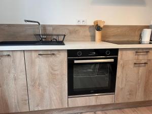 una cocina con armarios de madera y horno negro en Doux Pavillon - La suite Hirvi - Hyper centre, en Roanne