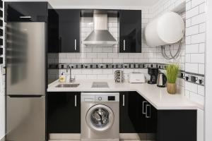 a kitchen with a stainless steel refrigerator and a washing machine at apartamento sevilla enzo in Seville