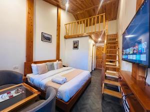 a bedroom with a bed and a tv and a staircase at Dwaper Palace A Luxury Property Near Library Chowk, Mussoorie in Mussoorie