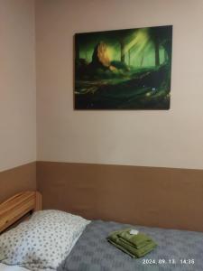 a bedroom with a bed and a painting on the wall at Vár-Liget Vendégház in Kisnána