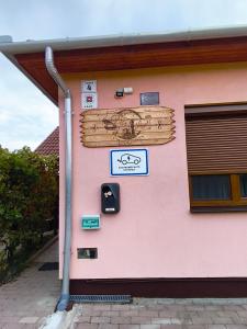 a pink building with a sign on the side of it at Vár-Liget Vendégház in Kisnána