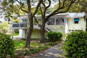 a yellow house with a porch and trees at The Salty Lime in Emerald Isle