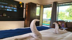 zwei aus einem Bett geformte Schwäne in einem Schlafzimmer in der Unterkunft Corbett Nature Walk - Forest View Swimming Pool in Rāmnagar