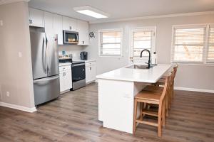 a kitchen with white cabinets and a stainless steel refrigerator at The Salty Lime in Emerald Isle