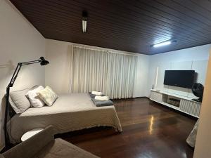 a bedroom with a bed and a flat screen tv at Villa Verde casa espaçosa com piscina e área verde no Lago Norte Brasilia in Brasília