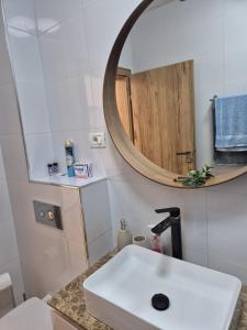 ein Badezimmer mit einem weißen Waschbecken und einem Spiegel in der Unterkunft Studio Valeria - Promenada Signature , Mamaia Nord in Năvodari