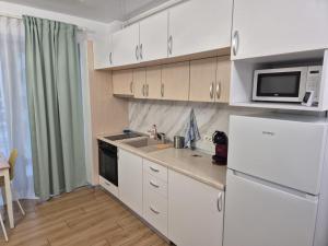 eine Küche mit einem weißen Kühlschrank und einer Mikrowelle in der Unterkunft Studio Valeria - Promenada Signature , Mamaia Nord in Năvodari