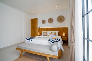 ein Schlafzimmer mit einem weißen Bett mit einem hölzernen Kopfteil in der Unterkunft Bali Taoka Villa Tanah Lot in Tanah Lot