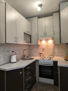 a kitchen with white cabinets and a stove top oven at Апарт Отель Элин in Svalyava