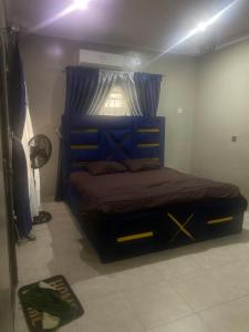 a bedroom with a large blue bed with a window at Flexy Short-let in Sagamu
