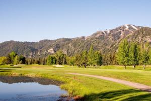 een golfbaan met een vijver en bergen op de achtergrond bij Leadville Condo 320 in Ketchum