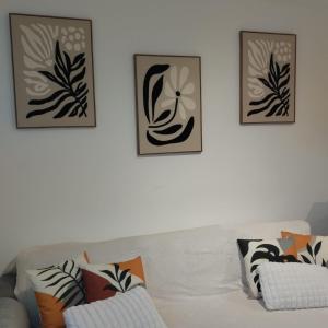 um sofá branco com três fotografias na parede em L'Alexandra em Noisy-le-Grand