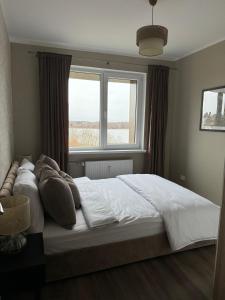 a bedroom with a large bed in front of a window at Lake View Apartment in Telšiai