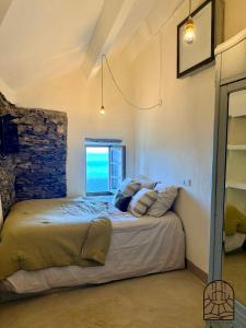 a bedroom with a bed with pillows and a window at Cap Hélios, Centuri in Morsiglia