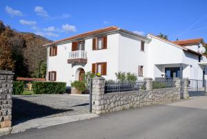 a white house with a stone fence at Apartment Lara in Lovran