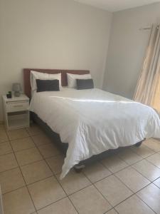 una camera da letto con un letto grande con lenzuola e cuscini bianchi di Stepney Apartment a Cape Town