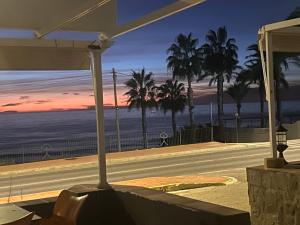 a street with palm trees and the ocean at sunset at El Flamenco in Mojácar