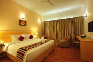 a hotel room with a large bed and a desk at Starlit Suites Kochi in Cochin