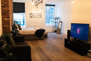 a living room with a bed and a flat screen tv at Chic Brighton Studio in Brighton & Hove