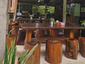 a large wooden table and stools in a restaurant at Modern Tor Tao camp in Ban Pak Suat