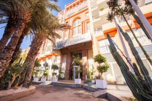 マラケシュにあるインペリアル ホリディ オテル ＆ スパの前にヤシの木がある建物