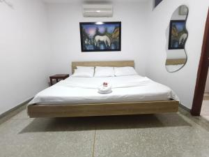 um quarto com uma cama grande e lençóis brancos em Hotel Los Arcangeles em Cúcuta