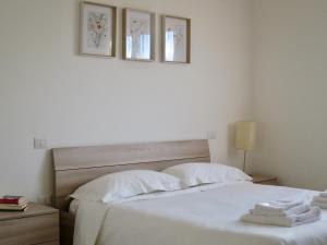 a bedroom with a white bed with three pictures on the wall at Lily House in Luino