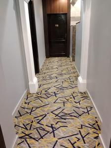 een gang met een tegelvloer voor een zwarte deur bij شقق المتميزين in Al Madinah