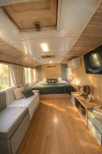 a living room with a couch and a bed in a trailer at Refúgio Da Lua - Buss motorhome in Ametista do Sul