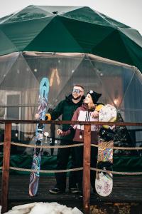 a man and a woman standing under a tent with snowboards at Góralski Harem Osada Glamp & Glass z Jacuzzi i Balią in Zakopane