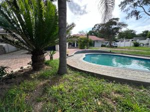 a swimming pool in a yard with a palm tree at StayAT62 in Nelspruit
