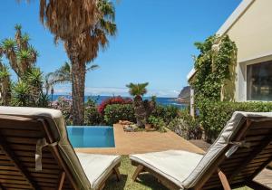 a backyard with two chairs and a swimming pool at Suite Vigia Jardim in Jardim do Mar